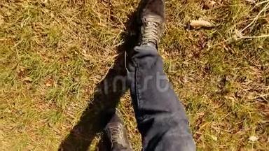一个穿着牛仔裤和运动鞋的男人的腿，<strong>在</strong>森林里的<strong>草地上行走</strong>，<strong>在</strong>日落时慢动作。